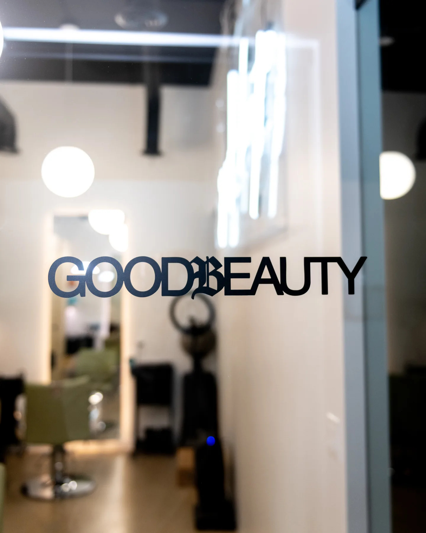 Good Beauty logo on the glass entry with the salon behind it